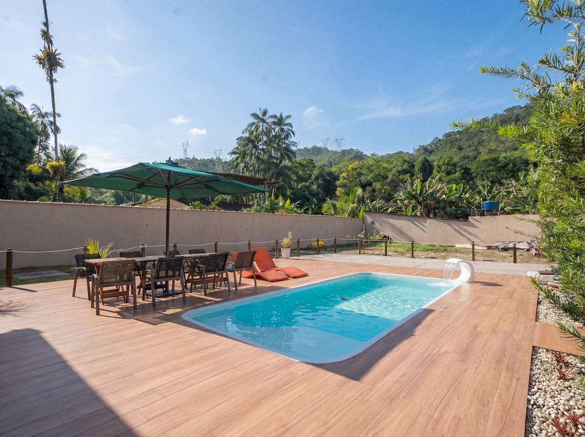Piscina com deck de madeira e montanhas ao fundo